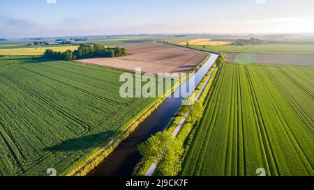 Strada diritta vicino al canale d'acqua in campagna pianeggiante Foto Stock