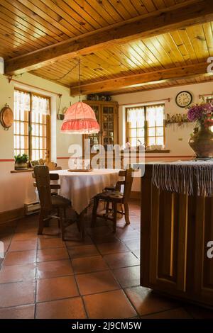 Antico tavolo e isola in cucina con pavimento in terracotta ceramica all'interno di una vecchia casa di tronchi ricostruita nel 1800s. Foto Stock
