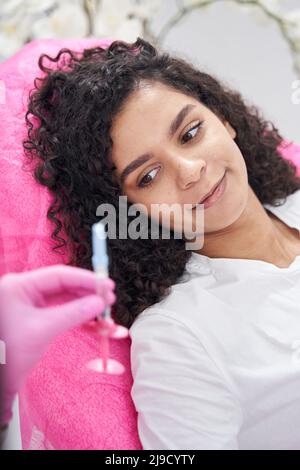 Lady guarda la piccola siringa nelle mani di un operatore medico Foto Stock