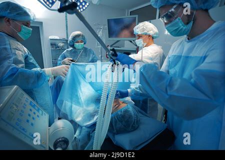 Anestesista che tiene premuta la maschera dell'ossigeno sul viso del paziente durante il funzionamento Foto Stock