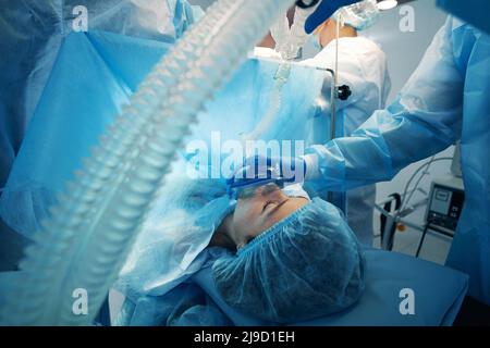 Medico che copre bocca e naso del paziente con maschera di rifornimento di ossigeno Foto Stock