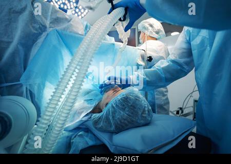 Maschera di pressione del chirurgo dell'apparecchio di respirazione di ossigeno al viso del paziente Foto Stock