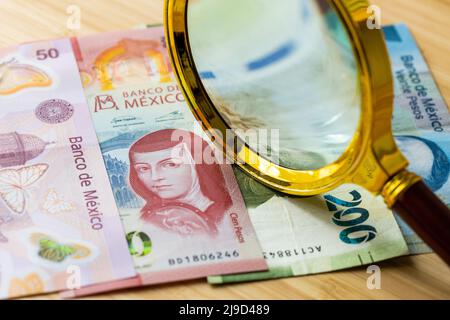 Soldi messicani, banconote sparse fuori sul tavolo, lente d'ingrandimento menzogne, concetto finanziario di affari di bilancio domestico Foto Stock
