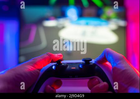 Il giocatore gioca a videogiochi con gli amici online. Nelle sue mani ha un gamepad moderno. Primo piano. Background tecnologico. Realtà virtuale, cyberspazio. Ad Foto Stock