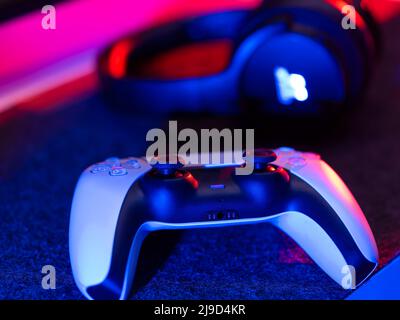 Primo piano di gamepad e cuffie. Accessori per videogiochi. Isolato su sfondo tecnologico. Illuminazione al neon. Non ci sono persone nella foto. Annuncio Foto Stock