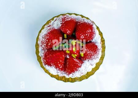 Mini tartina di fragole cosparso di zucchero a velo, pasta delicata, isolata su piatto bianco Foto Stock