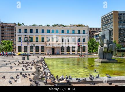 Atene, Grecia - Maggio 21 2022: Il vecchio municipio in via Athinas, attraverso Piazza Kotzia, con molti piccioni poggiati presso la fontana. Foto Stock