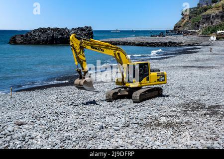 Un escavatore Komatsu DC210 che appiattisce le pietre sul lungomare di San Martinho, Madeira. Foto Stock