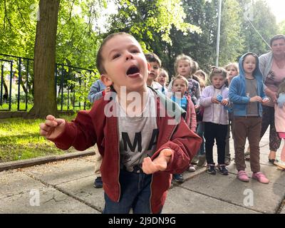 Lviv, Ucraina. 16th maggio 2022. Un ragazzo orfano ucraino sconfinato si aggira intorno per la macchina fotografica mentre gli altri adorabili orfani e bambini rifugiati si allineano a cantare, sui terreni di legno dell'orfanotrofio di Lviv. L'orfanotrofio sta attualmente ospitando alcuni bambini con le loro famiglie che sono fuggiti qui con i loro genitori da altre città dilaniate dalla guerra in Ucraina, insieme ai ragazzi e alle ragazze che sono diventati senza parentela prima della brutale invasione della Russia, e per questo motivo. (Credit Image: © Amy Katz/ZUMA Press Wire) Foto Stock