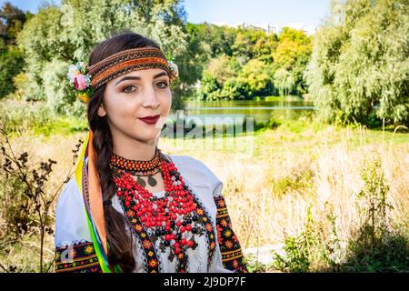 Una donna Ucraina in una camicia ricamata si erge sulla riva del fiume. Foto Stock