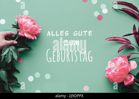 Biglietto d'auguri con fiori rosa di peonia su sfondo verde sbiadito, spazio di testo. Elegante, informale, vista dall'alto, ecologico e naturale. Compleanno estivo Foto Stock