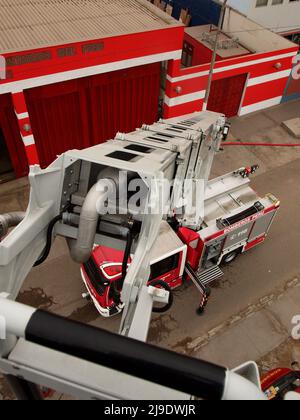 Un camion di pompiere Magirus Iveco 180E28 dal corpo generale dei pompieri volontari del Perù - CGBVP - estendendo la sua gru telescopica Foto Stock