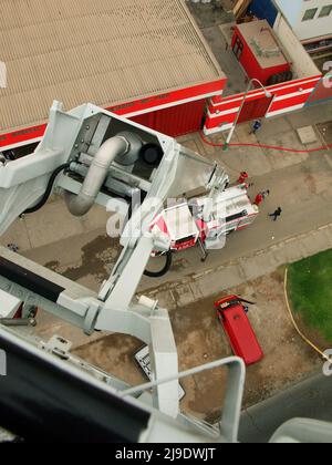 Un camion di pompiere Magirus Iveco 180E28 dal corpo generale dei pompieri volontari del Perù - CGBVP - estendendo la sua gru telescopica Foto Stock