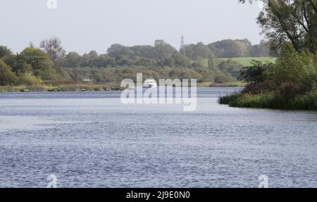 Cruiser a motore bianco sul fiume d'acqua dolce con le bancarelle di pesca - il fiume Erne a Enniskillen, Contea di Fermanagh, Irlanda del Nord. Foto Stock