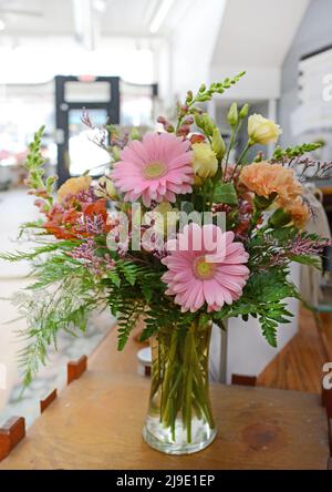 Fiori freschi disposti in una stanza illuminata dal sole. Margherite di gerbera e una varietà graziosa di altri fiori rosa. Foto Stock