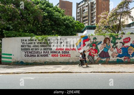 22 maggio 2022, Caracas, Miranda, Venezuela: Una donna e suo figlio passano di fronte a un murale con immagini di venezuelani espulsi a zio Sam (Stati Uniti d'America) con una frase del defunto presidente Hugo Chavez ... Venezuela non sarà mai più una colonia di nessuno. (Credit Image: © Jimmy Villalta/ZUMA Press Wire) Foto Stock