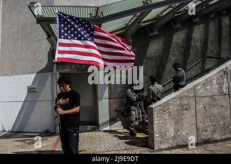 Un protestante canta l’inno nazionale americano mentre tiene la bandiera americana per simboleggiare la democrazia, mentre gli ufficiali di polizia in preda alla rivolta guardano via. Le proteste a favore della democrazia sono scoppiate e si sono intensificati in conflitti urbani quando il governo di Hong Kong, sotto il governo cinese, ha rifiutato di ritirare un controverso disegno di legge sull'estradizione e ha condonato la brutalità della polizia contro i manifestanti inizialmente pacifici. Foto Stock