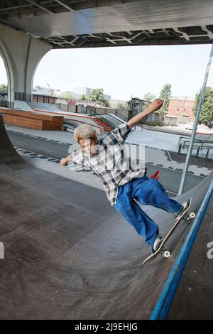 Azione di un adolescente di strada che guida skateboard sulla rampa al parco di pattinaggio e fare trucchi, spazio copia Foto Stock