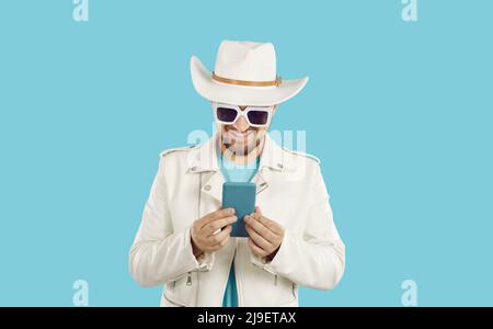 Un uomo allegro e alla moda che utilizza un cellulare moderno comunica con gli amici online sui social network. Foto Stock