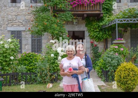 Primo piano ritratto di famiglia di due donne che stanno posando sullo sfondo del cortile estivo. Foto Stock