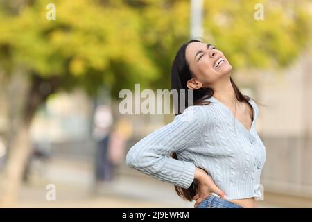 Donna stressata che lamenta sofferenza lumbago attacco a piedi per strada Foto Stock