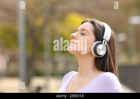 Rilassato teen meditating con cuffie guida di ascolto in un parco Foto Stock