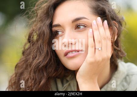 Donna fiduciosa che mostra anello di fidanzamento guardando lato dopo proposta Foto Stock