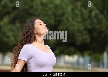 Donna rilassata respirando aria fresca in piedi in un parco Foto Stock