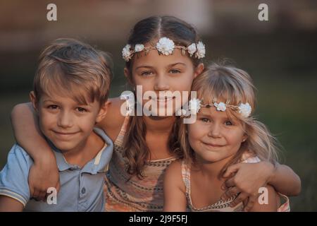 Ritratto di un adorabile Bambini all'aperto. Elegante look primaverile. Baby moda. Due sorelle con il loro fratello che si divertono nel cortile. Foto Stock