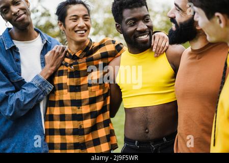 Giovani uomini diversi che si abbraccia a vicenda al parco della città - Focus su gay uomo indossare make-up Foto Stock