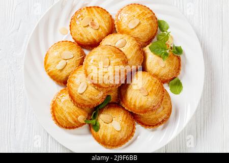 Biscotti di mandorle olandesi ripieni di pasta di marzapane e mandorle noci, gevulde koek, su piatto bianco su tavola di legno bianco, piatto, primo piano Foto Stock