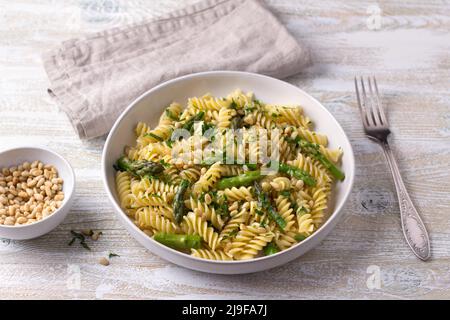 Pasta vegana con asparagi, aglio, pinoli e prezzemolo su sfondo di legno, vista dall'alto. Semplice cibo fatto in casa Foto Stock