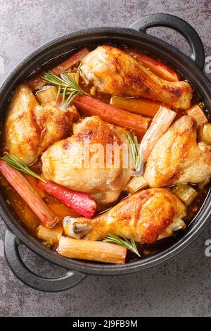 Pollo al forno con rabarbaro e vino bianco in una padella sul tavolo. Vista dall'alto verticale Foto Stock