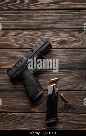 Pistola e cartucce per esso su sfondo di legno. Un'arma a corto-barreled per autodifesa. Foto Stock