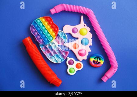 giocattoli colorati di fidget sensoriali antistress su sfondo blu Foto Stock