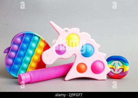 giocattoli colorati di fidget sensoriali antistress su sfondo grigio Foto Stock
