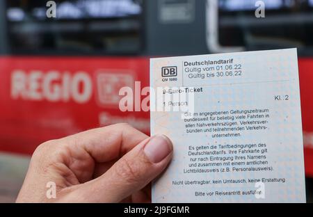 Lipsia, Germania. 23rd maggio 2022. Una donna ha un biglietto di 9 euro davanti a un treno regionale espresso della Deutsche Bahn (DB) presso la stazione centrale di Lipsia. La gente in Sassonia potrà acquistare il biglietto da 9 euro per i mezzi pubblici locali a partire da lunedì. Il biglietto è di solito disponibile presso distributori automatici, punti vendita o autisti di autobus e sarà valido in tutta la nazione a partire da giugno 1. Credit: Jan Woitas/dpa/Alamy Live News Foto Stock