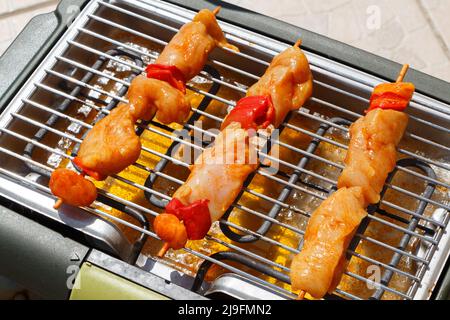 Brocetta di pollo marinata cruda sulla griglia di un barbecue elettrico Foto Stock
