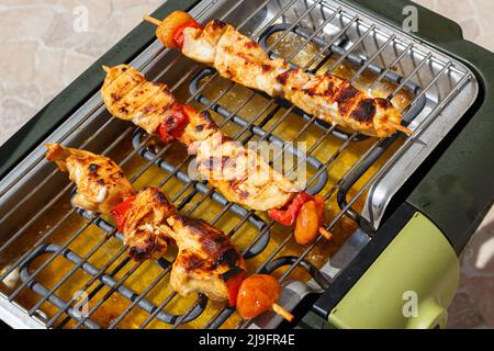 Brochette di pollo marinate sulla griglia di un barbecue elettrico durante l'estate Foto Stock