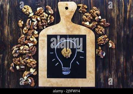 lampadina disegnata con gustose noci sgranate su sfondo di legno Foto Stock