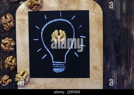 lampadina disegnata con gustose noci sgranate su sfondo di legno Foto Stock