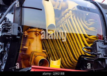 Vecchia locomotiva a vapore retrò nera e rossa presso la stazione ferroviaria con vista su un tubo interno. Vintage treno che rimane sulla ferrovia. Foto Stock