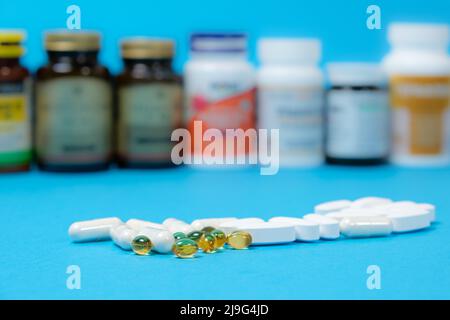Medicinali o integratori alimentari su sfondo blu e vasi con pillole sullo sfondo. Foto Stock
