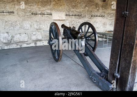 cannone da tiro con ruote dal medioevo di fronte ad un muro di pietra bianca, oggetto ideale per liberare per composizioni fotografiche, metallo nero-marrone, i Foto Stock