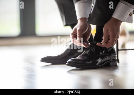 Lo sposo fissa le scarpe con le sue scarpe nere lucide in un giorno di nozze. Foto Stock