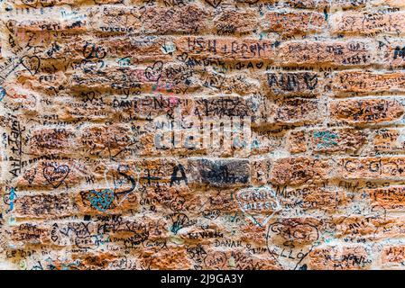 Verona, Italia - 20 settembre 2021: Muro di pietra accanto alla casa di Giulietta, a Verona, dove gli amanti lasciano le loro firme e i loro messaggi d'amore. Foto Stock