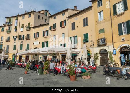 Persone in ristoranti e caffè in Piazza dell'Anfiteatro nel centro storico di Lucca, Toscana Foto Stock