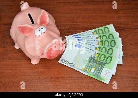 rosa piggy banca con banconote da 100 euro Foto Stock