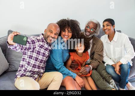 Famiglia felice di multi-generazione che prende un selfie nel soggiorno Foto Stock