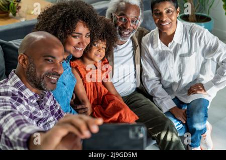 Famiglia felice seduta sul divano mentre prende selfie Foto Stock